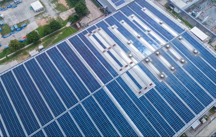 Luftaufnahme einer großflächigen Photovoltaikanlage auf einem Industriedach